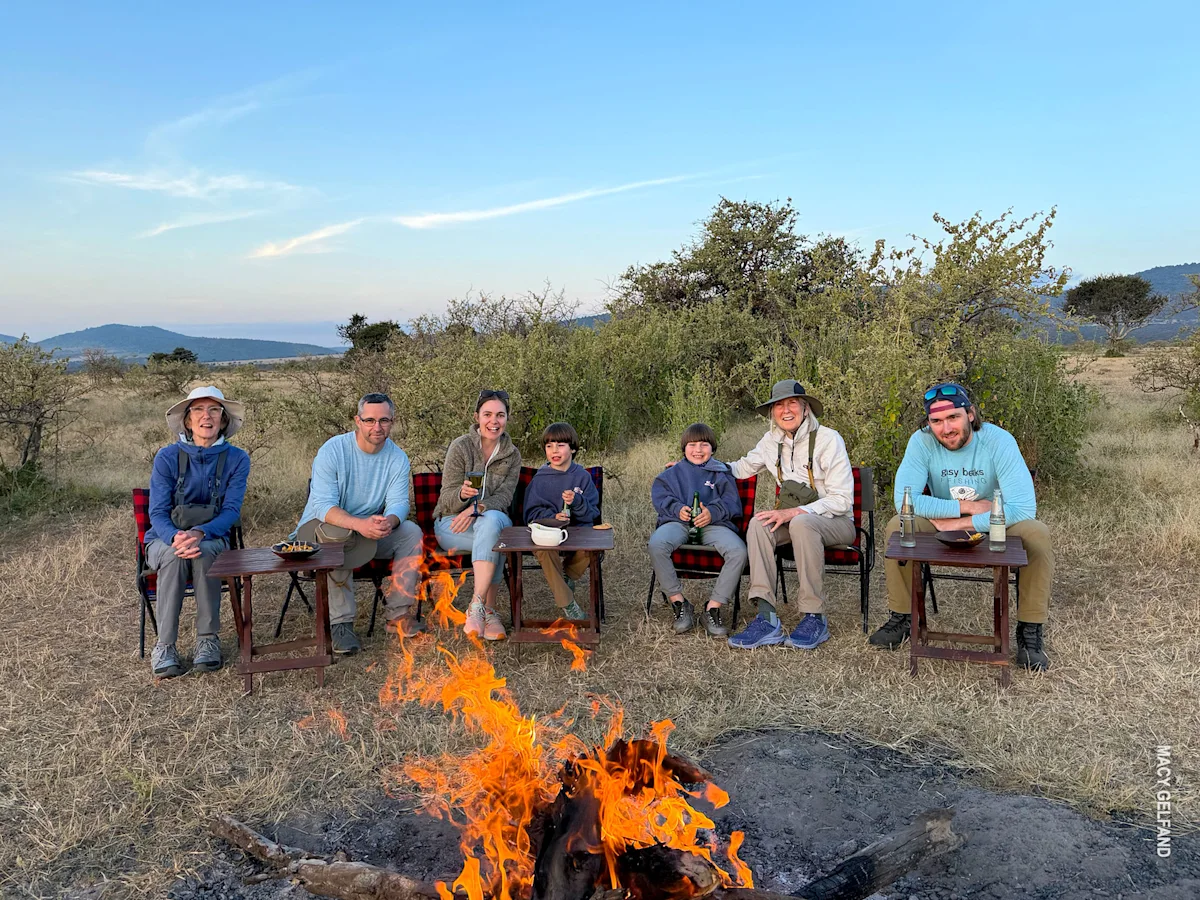 multi generations sit around campfire at end of day at thomson serengeti nyumba camp during family safari