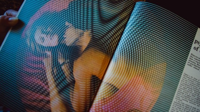 Et åbent magasin med et farverigt, forvrænget billede trykt på siderne, set i dæmpet belysning.