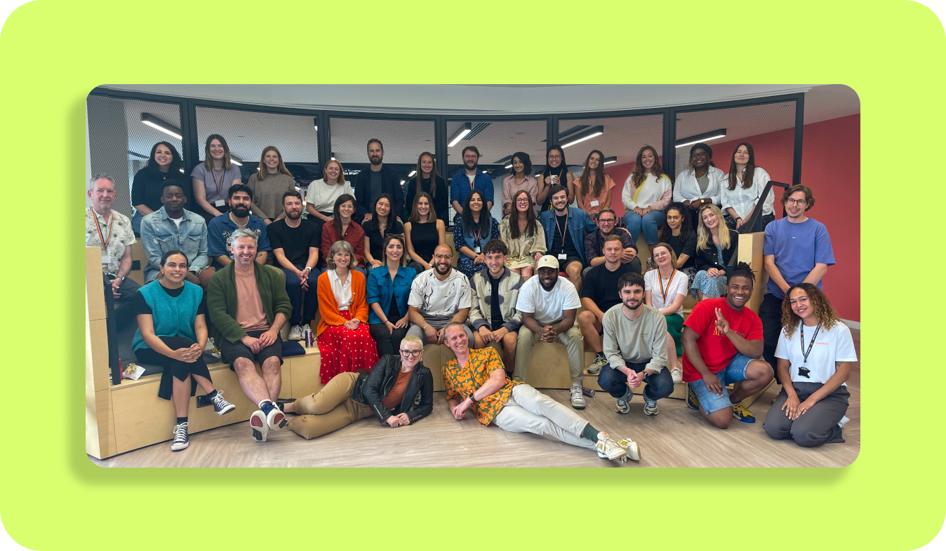 40 researchers and designers are sitting on bleachers and smiling. 