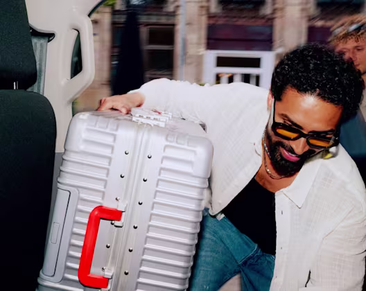 Man carrying a large suitcase into a taxi