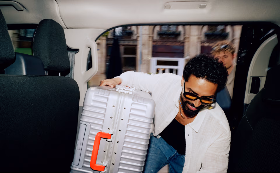 Person getting into a taxi with a suitcase 