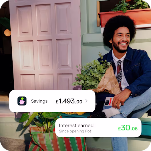A man wearing double denim smiling sat on a porch in the sun. He's carrying a bunch of flowers. Overlaid is the Monzo Savings notification showing a savings total of £1,493.