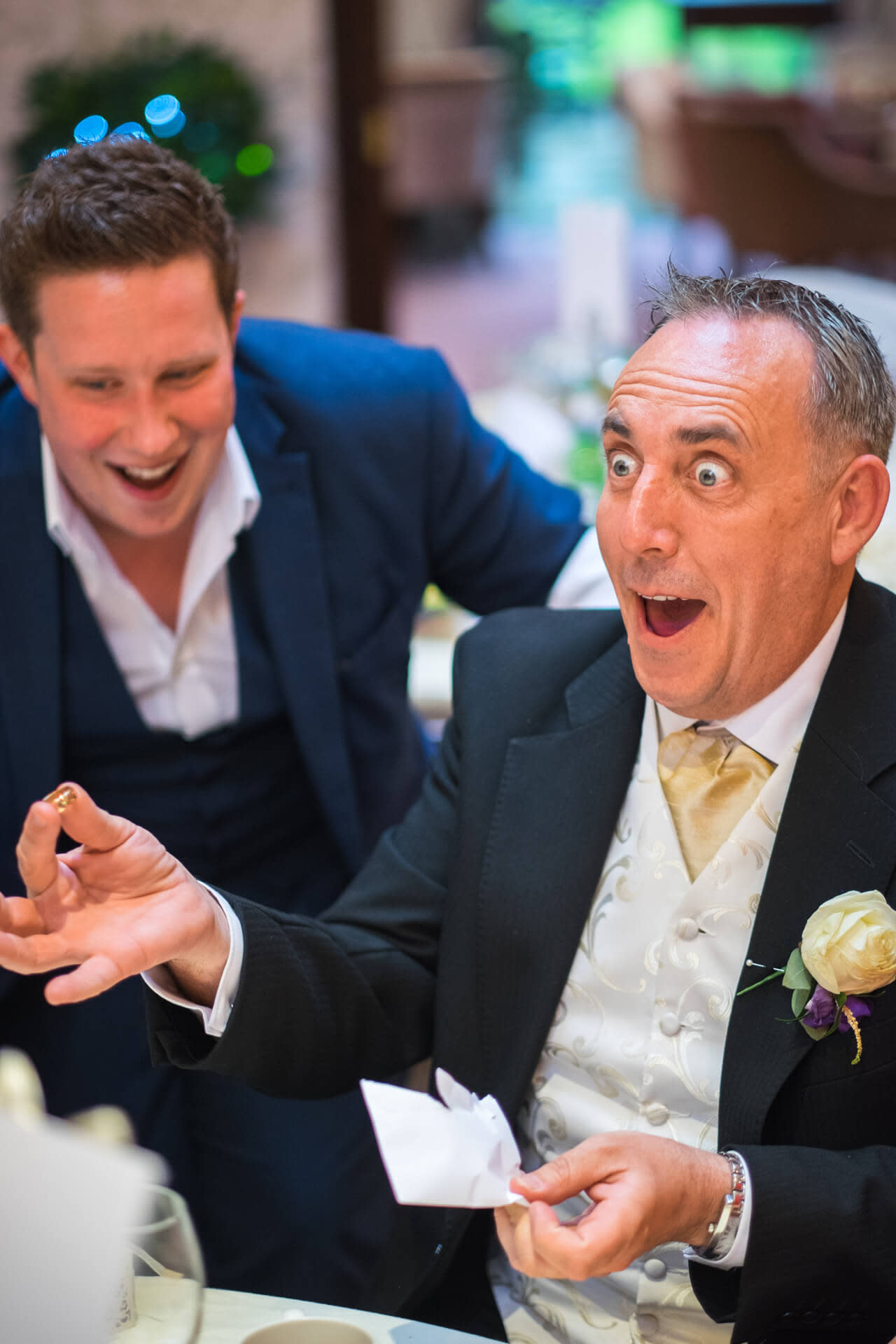 Two men at a wedding, one's amazed by a magic trick