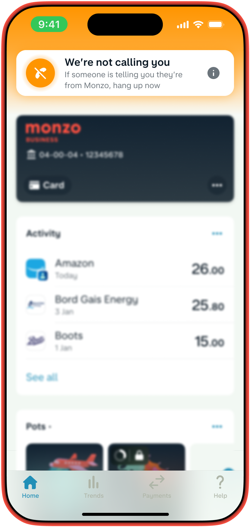 Monzo bank app alert on a smartphone: "We're not calling you. If someone claims to be from Monzo, hang up." The screen shows recent transactions, including payments to Amazon, Bord Gais Energy, and Boots. Navigation icons at the bottom include Home, Trends, Payments, and Help.