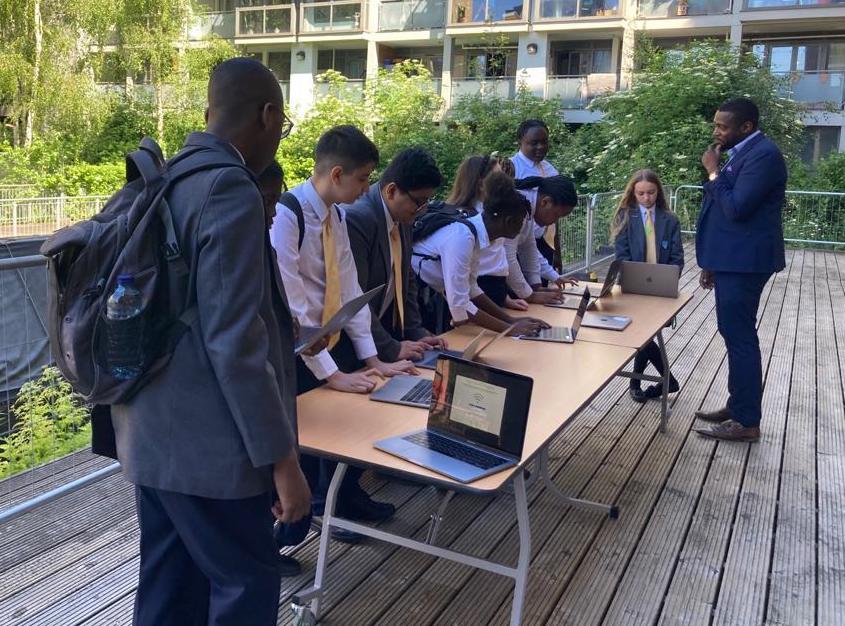 A group of school children along a desk setting up their new laptops