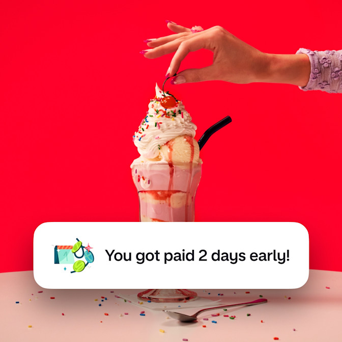 A woman's arm putting a cherry on top of an ice cream sundae against a red background. There is an image of a calendar with coins around it and text next to it saying You got paid two days early!