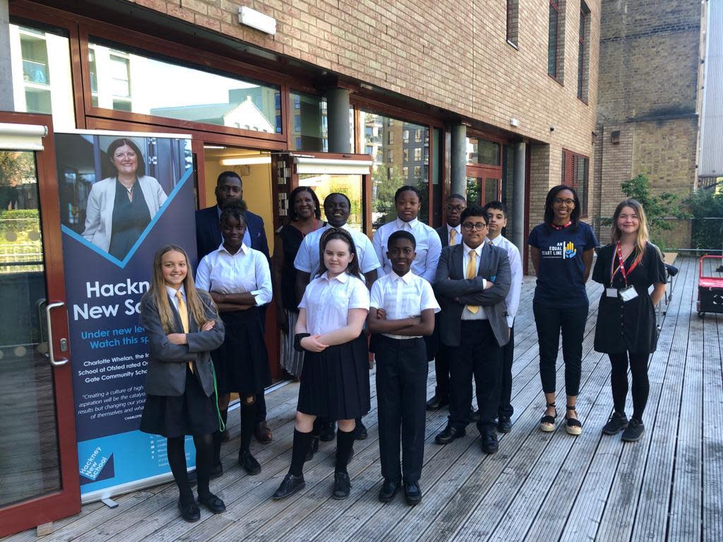 A group of Hackney New School teachers and pupils standing outside on some decking