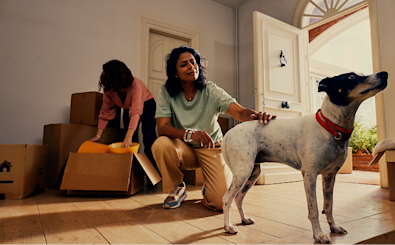 Two people and their dog in an empty room in a new house