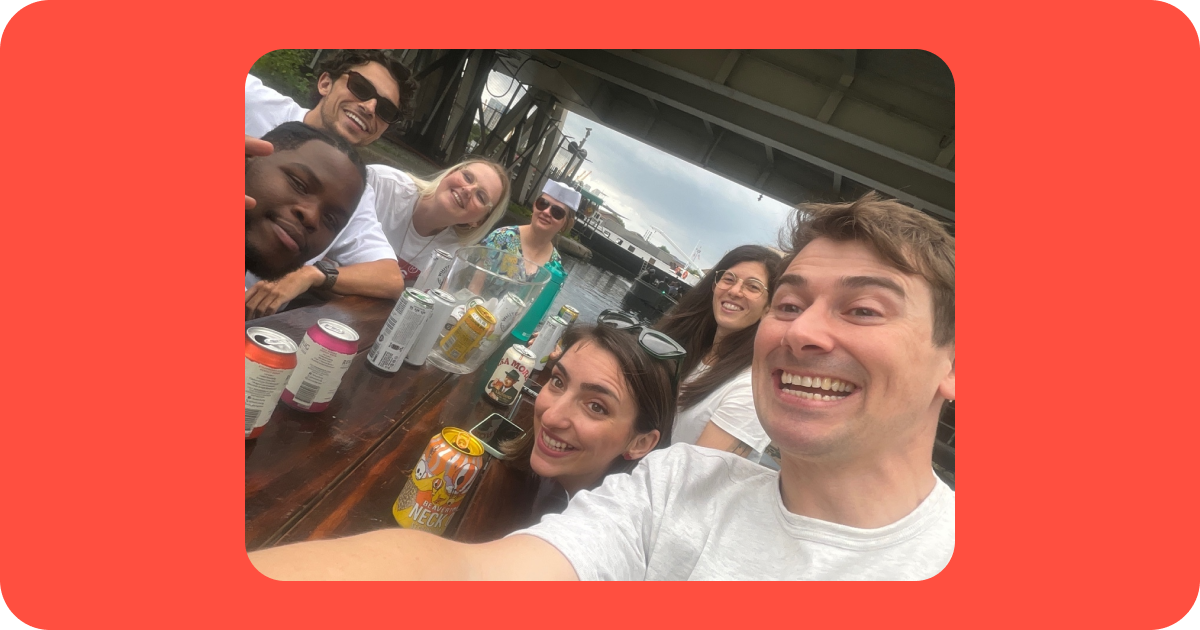 Seven Monzo designers smiling together on a boat during a team social in Canary Wharf.