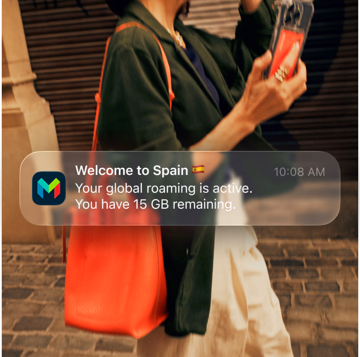 A person holds a phone with a monzo card with a popup notification reading 'Welcome to Spain. Your global roaming is active. You have 15 gigabites remaining.'