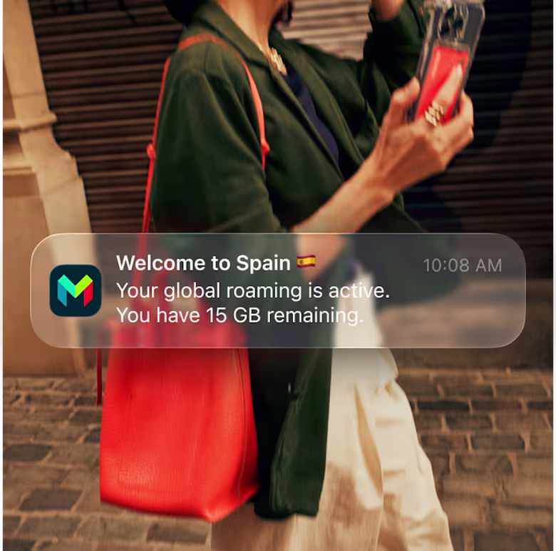 A person holds a phone with a monzo card with a popup notification reading 'Welcome to Spain. Your global roaming is active. You have 15 gigabites remaining.'
