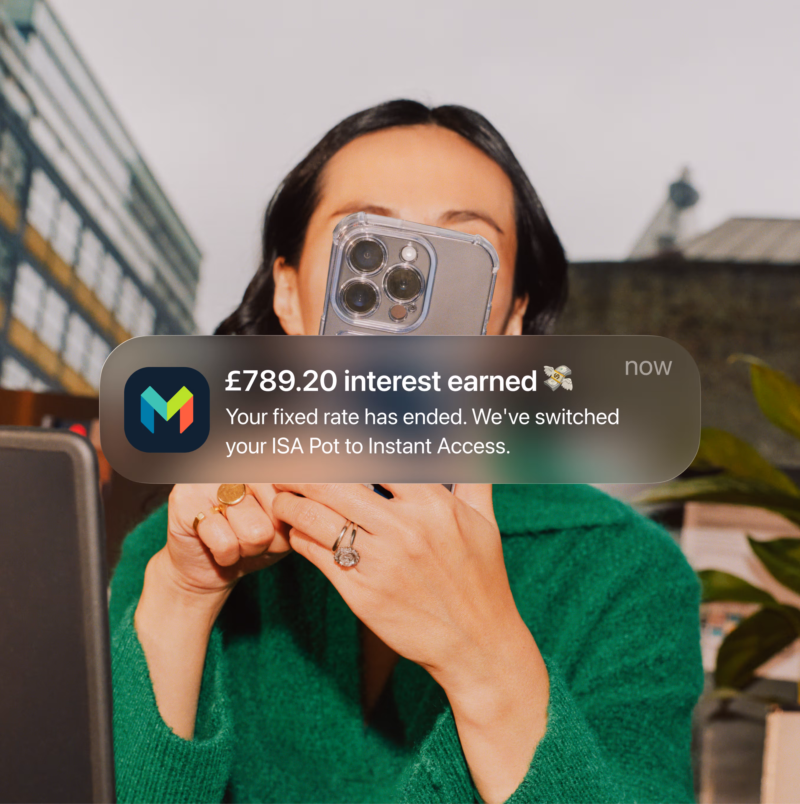 A woman looking at her smartphone with a notification overlaid showing that she has earned £789.20 in interest.