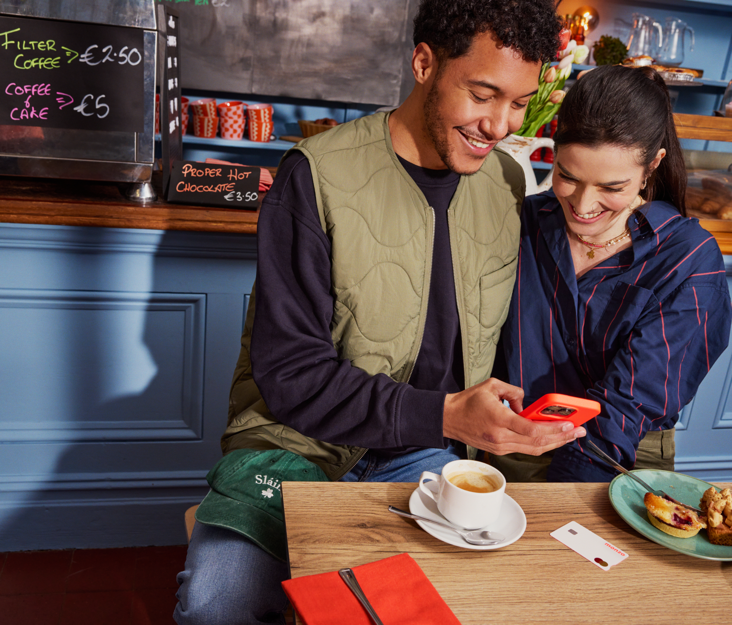 Couple in cafe checking their phone over coffee