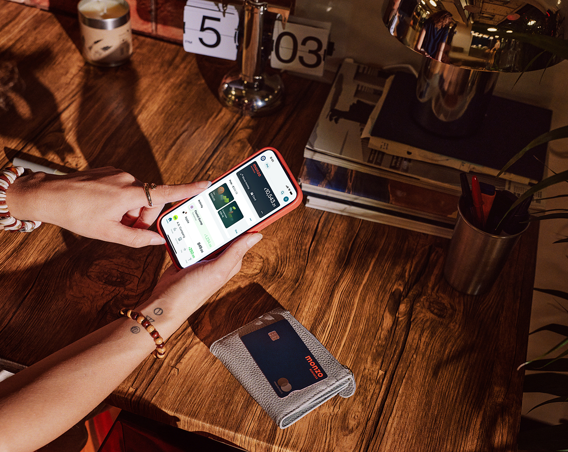 Mobile phone open on the Monzo business screen which Monzo debit card on the table