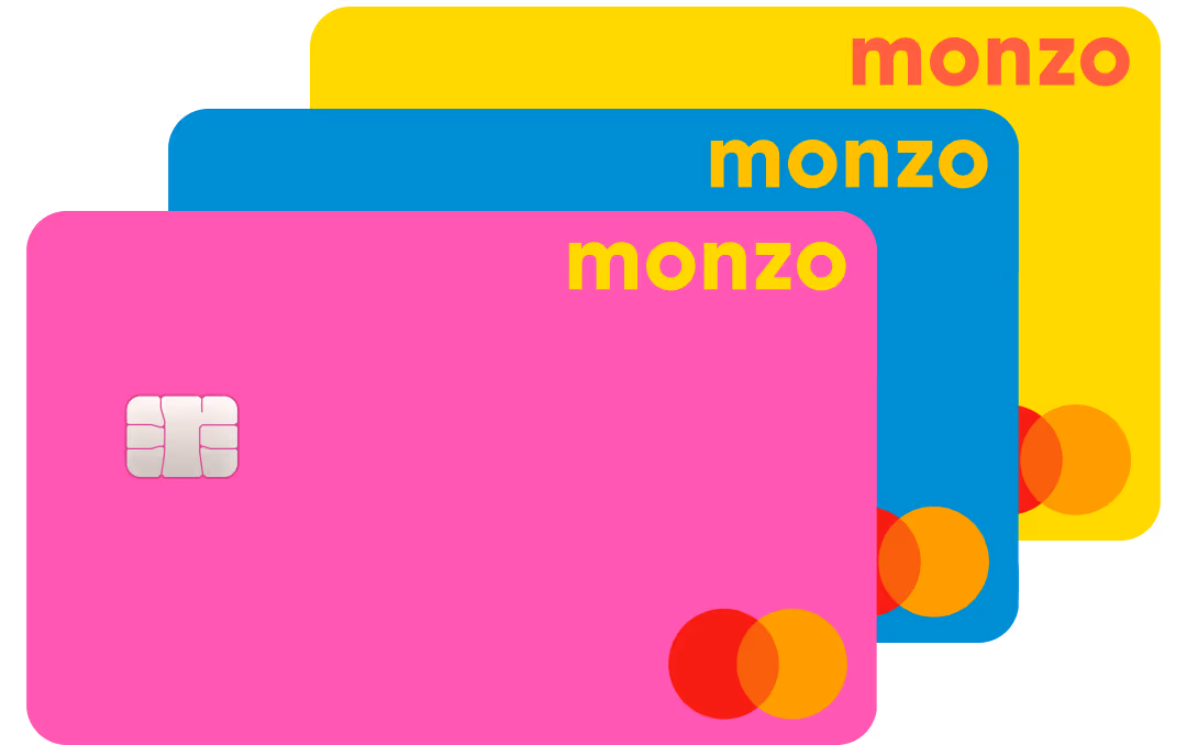 Three colourful Monzo bank cards layered behind one another. The cards are pink, blue, and yellow, each featuring the Monzo logo, a payment chip, and the Mastercard logo in the corner.