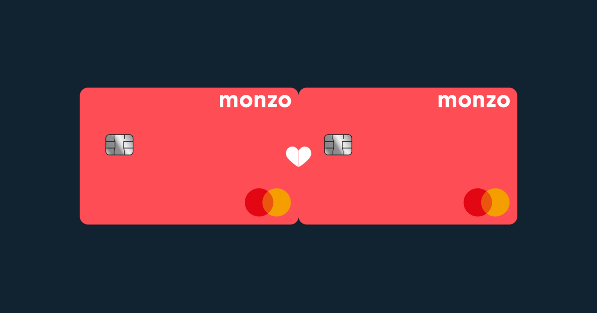 Two hot coral Monzo cards side-by-side with a white heart overlapping them in the middle