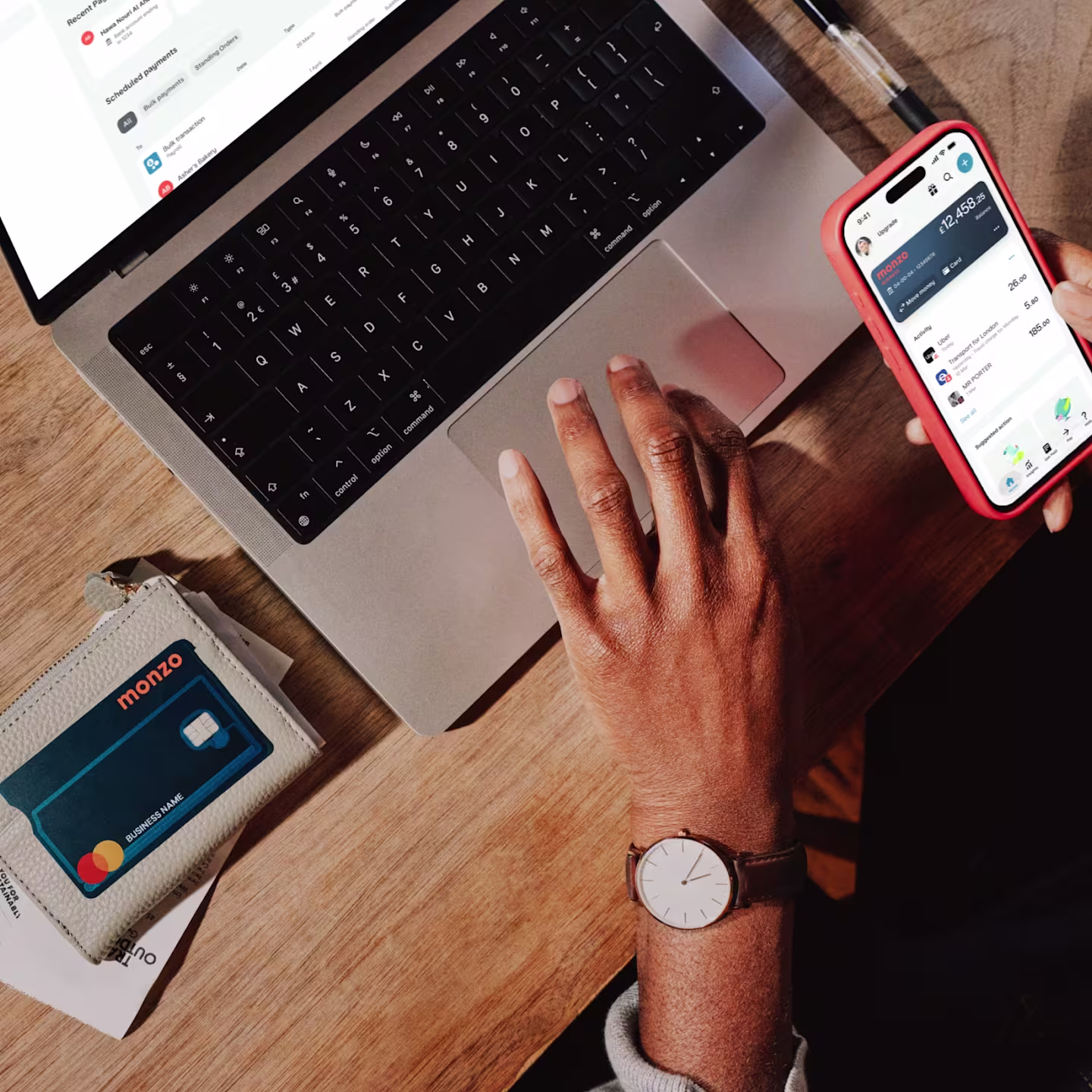 A business owner doing online banking with Monzo Business on their phone, with a business account card laid over the top