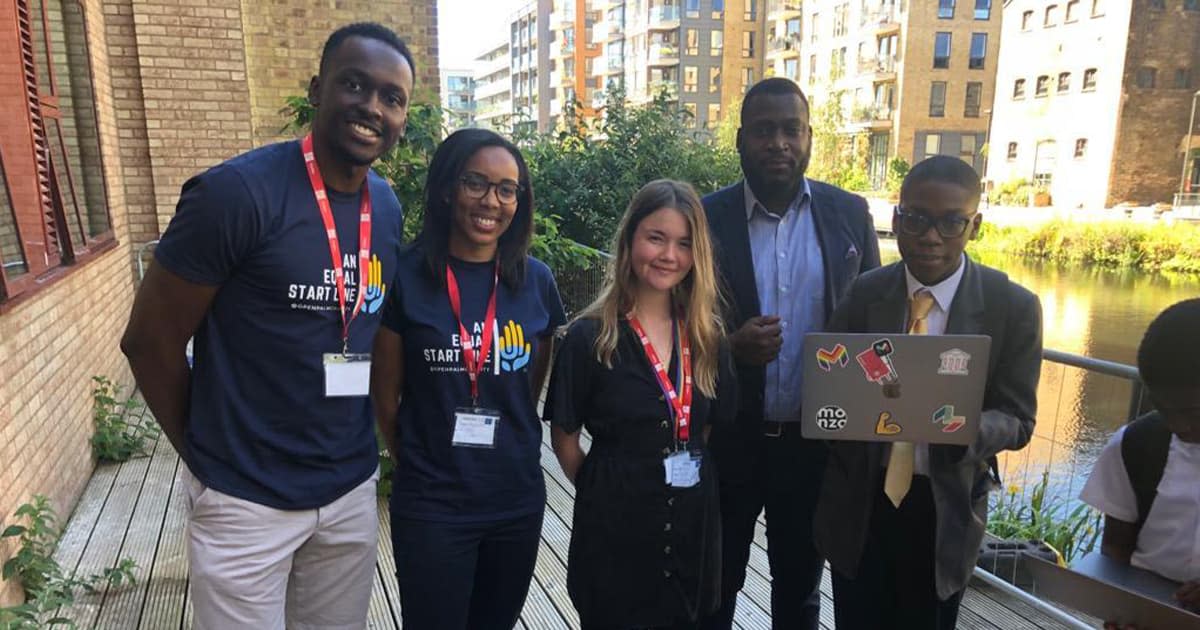 Some teachers, pupils, and Jess from Monzo standing in a row with a laptop