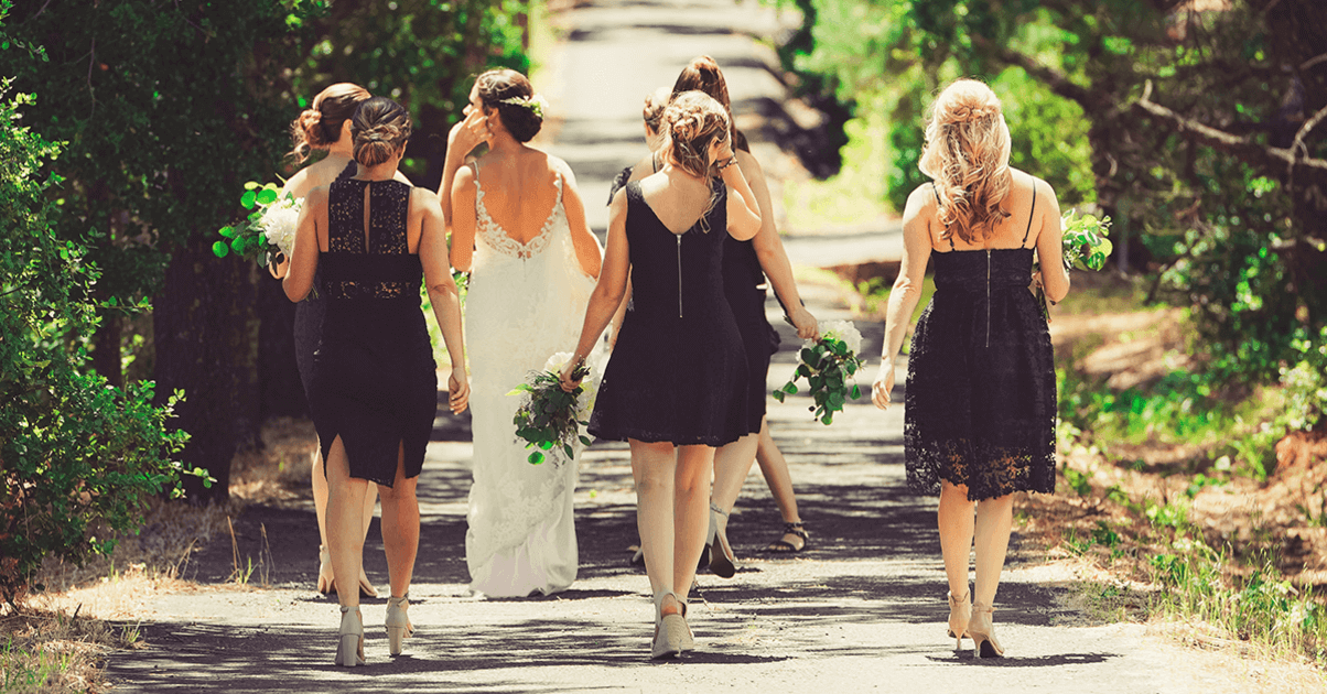 bride and bridesmaids walking down green path