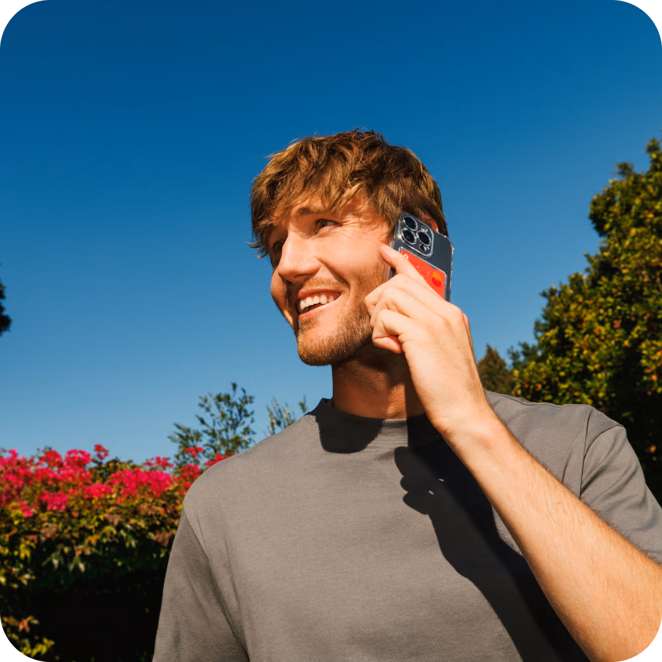 A man holds a phone next to his ear, and is smiling