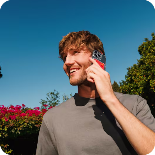 A man holds a phone next to his ear, and is smiling