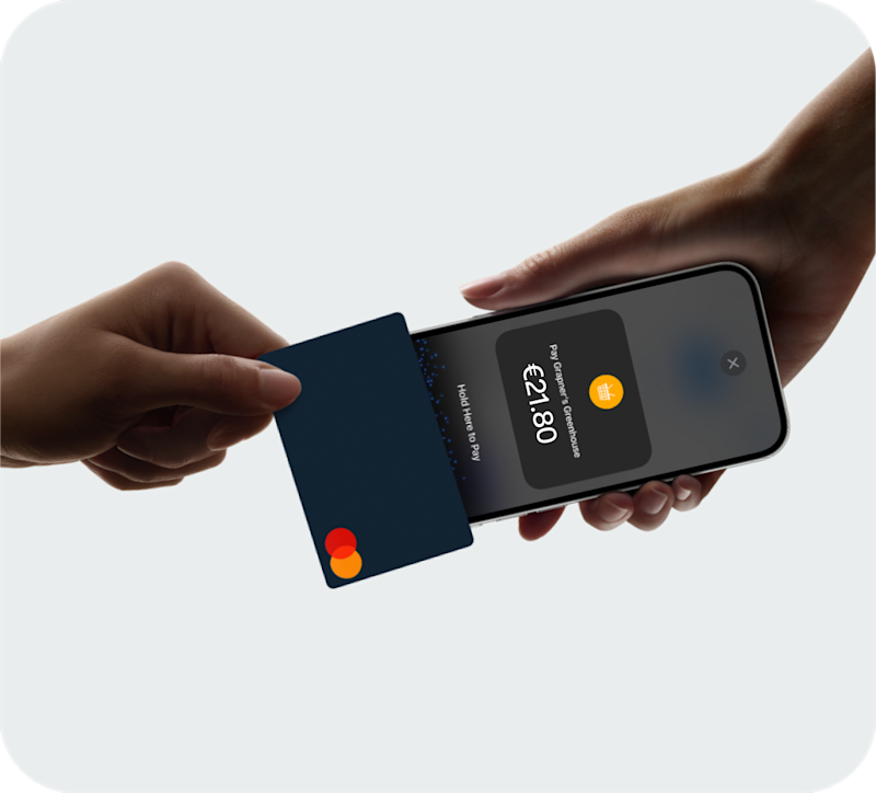 Person holding a smartphone while another hand taps a bank card against it to make a contactless payment of €21.80