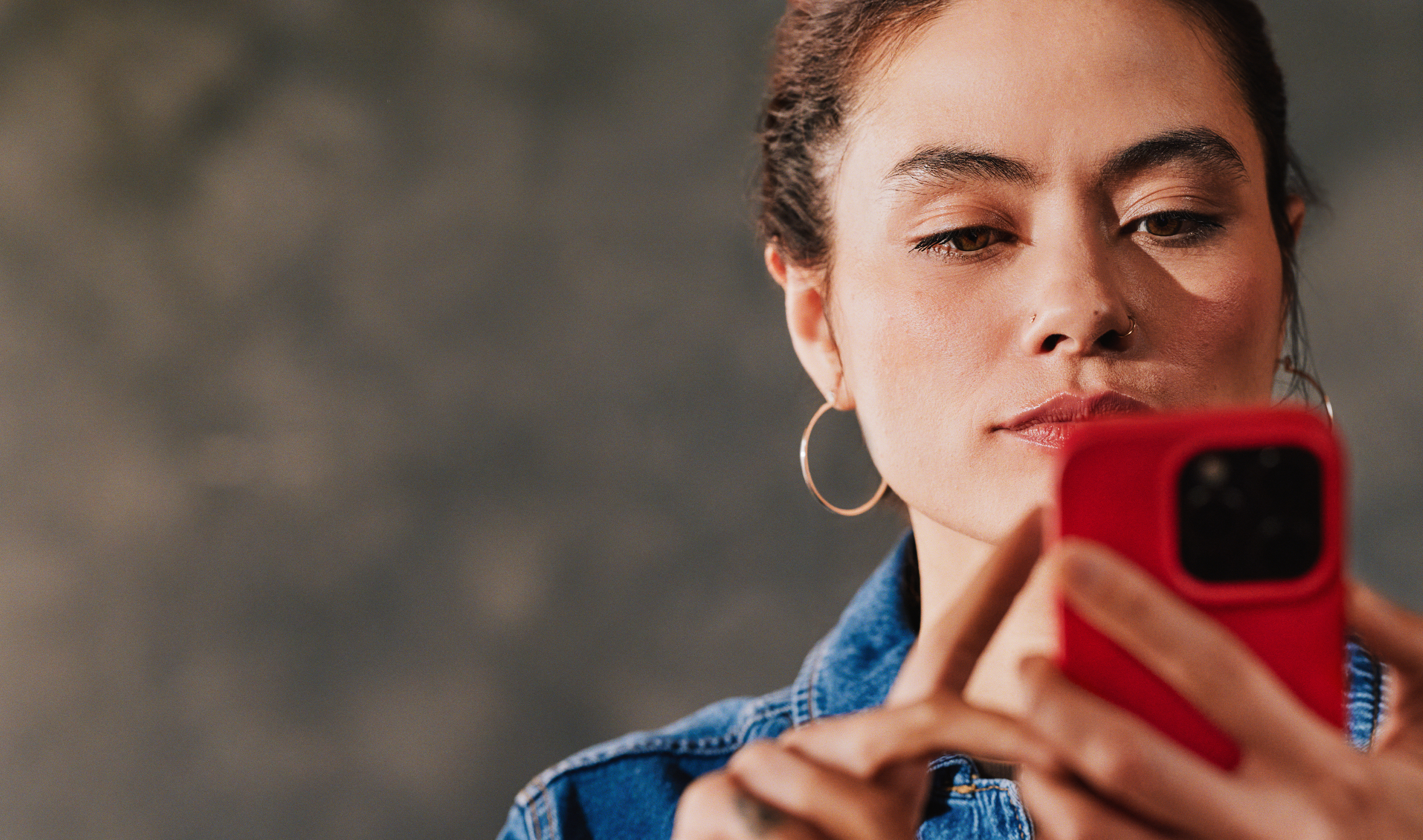 Woman looking at a phone with a hot coral case