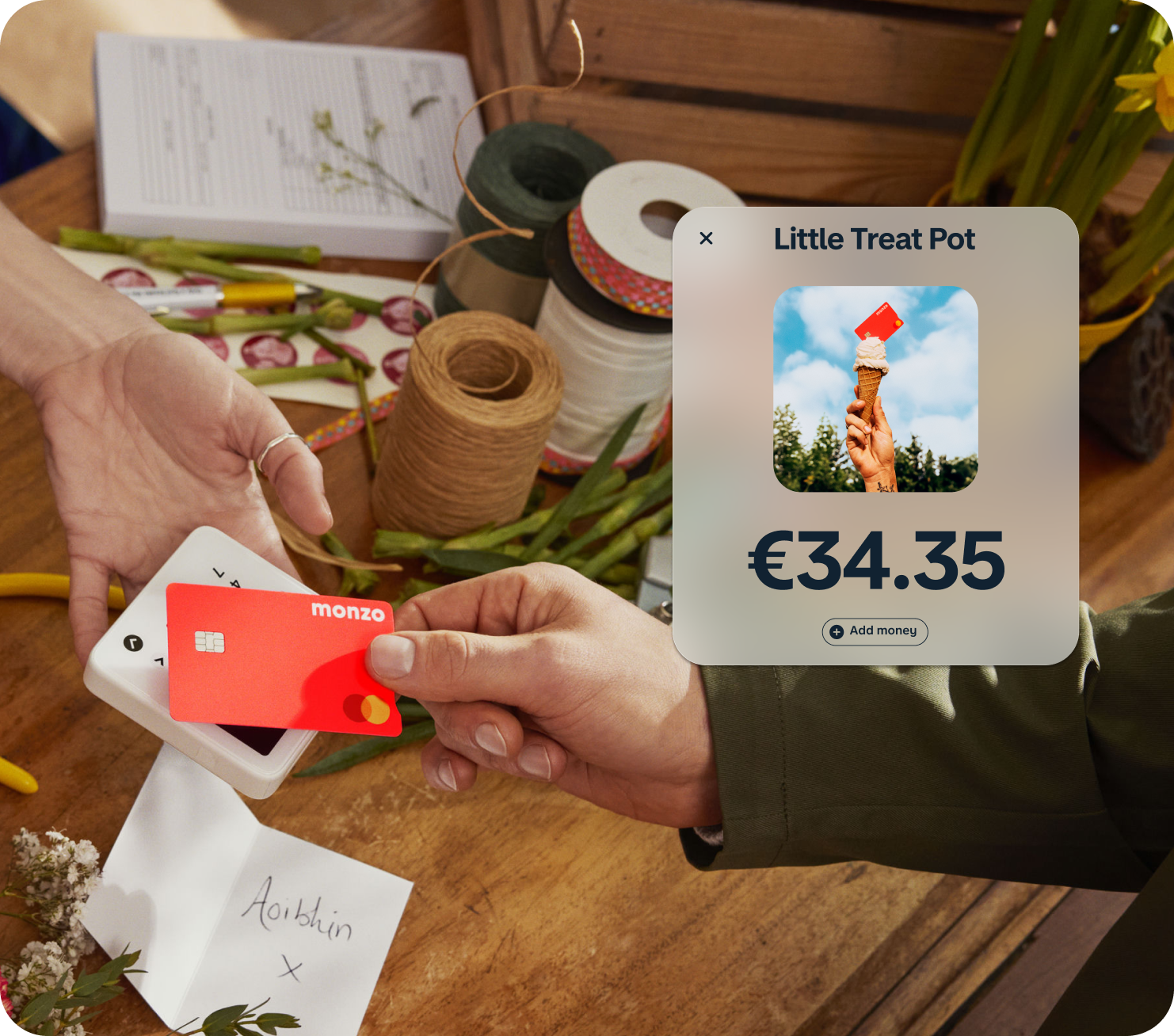 Person paying with their Hot Coral Monzo card. Product UI is overlayed on the image showing a Pot called 'Little Treat Pot'