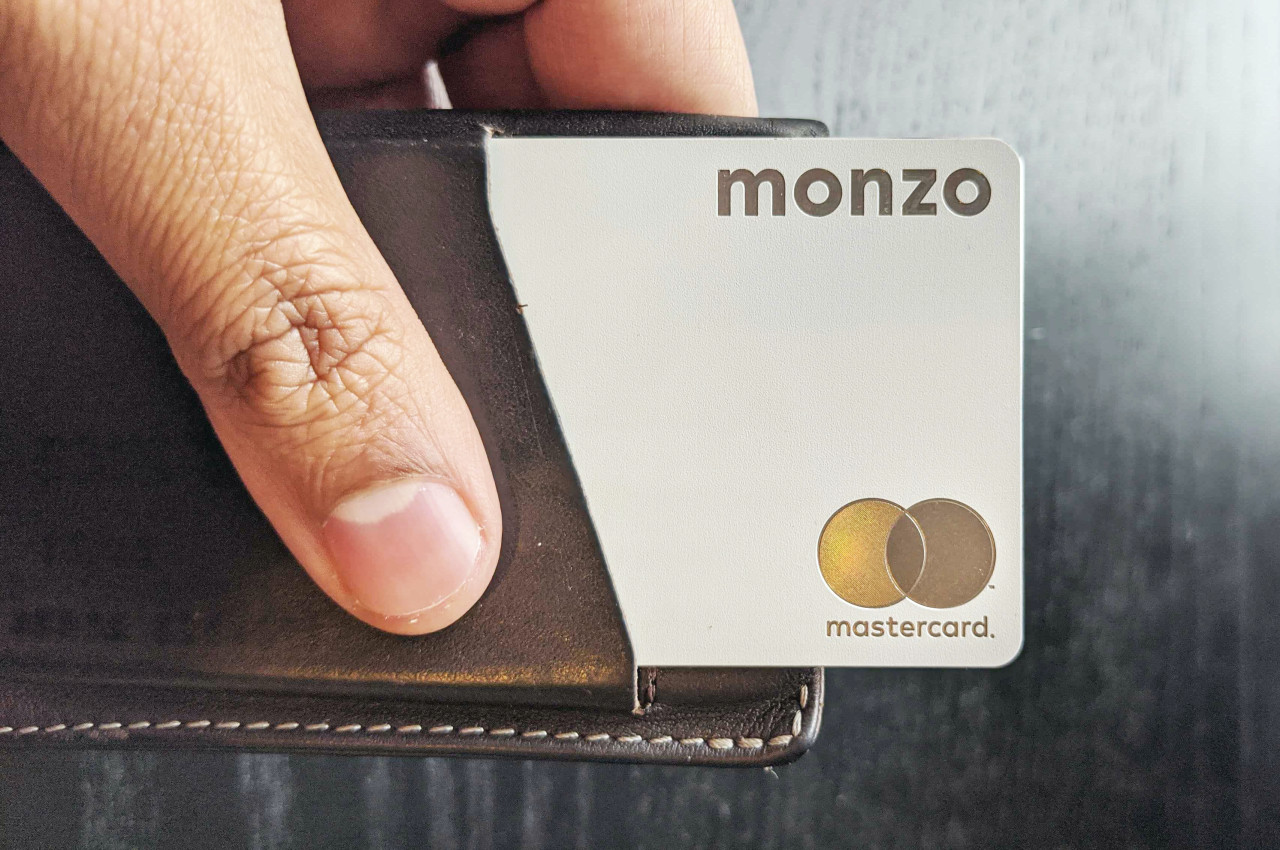 A metal Monzo card poking up out of a leather wallet