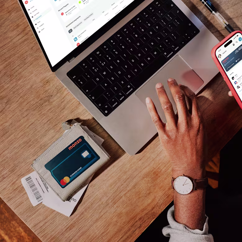 A birds eye view of some hands typing on a laptop, with a Monzo Business card to the side