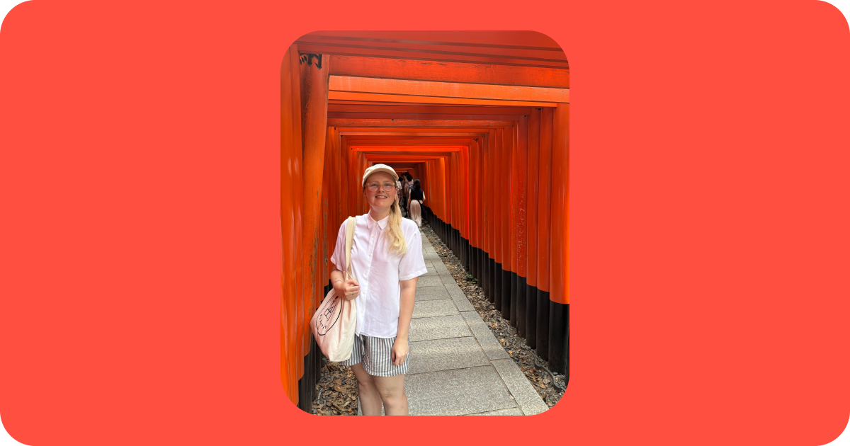Kelly (the author) standing by a row of large orange gates in Kyoto, Japan.