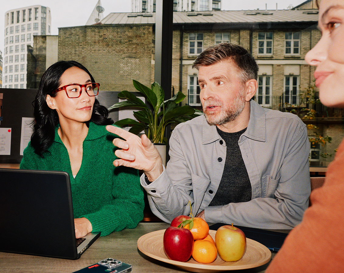 A man and two women having a discussion around a table with a laptop