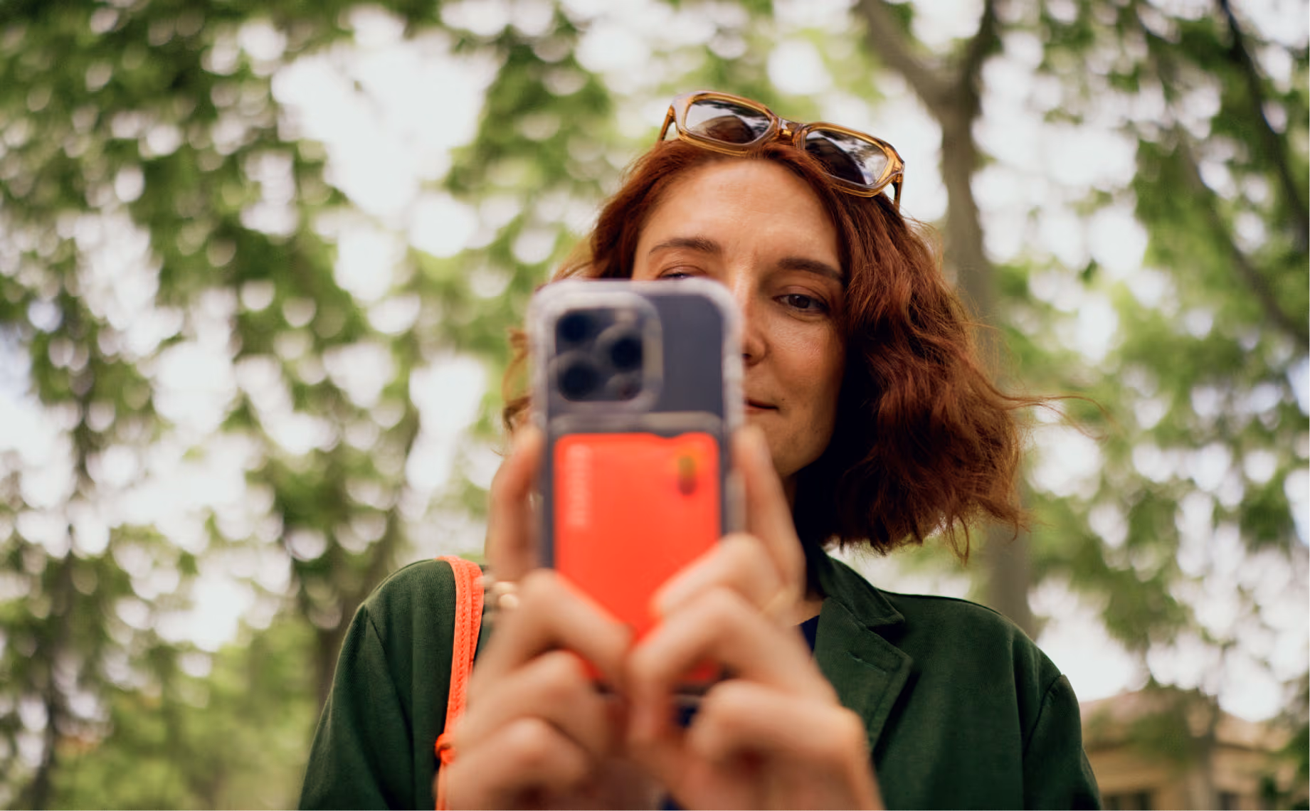 A woman using her phone with a view of trees in the background.