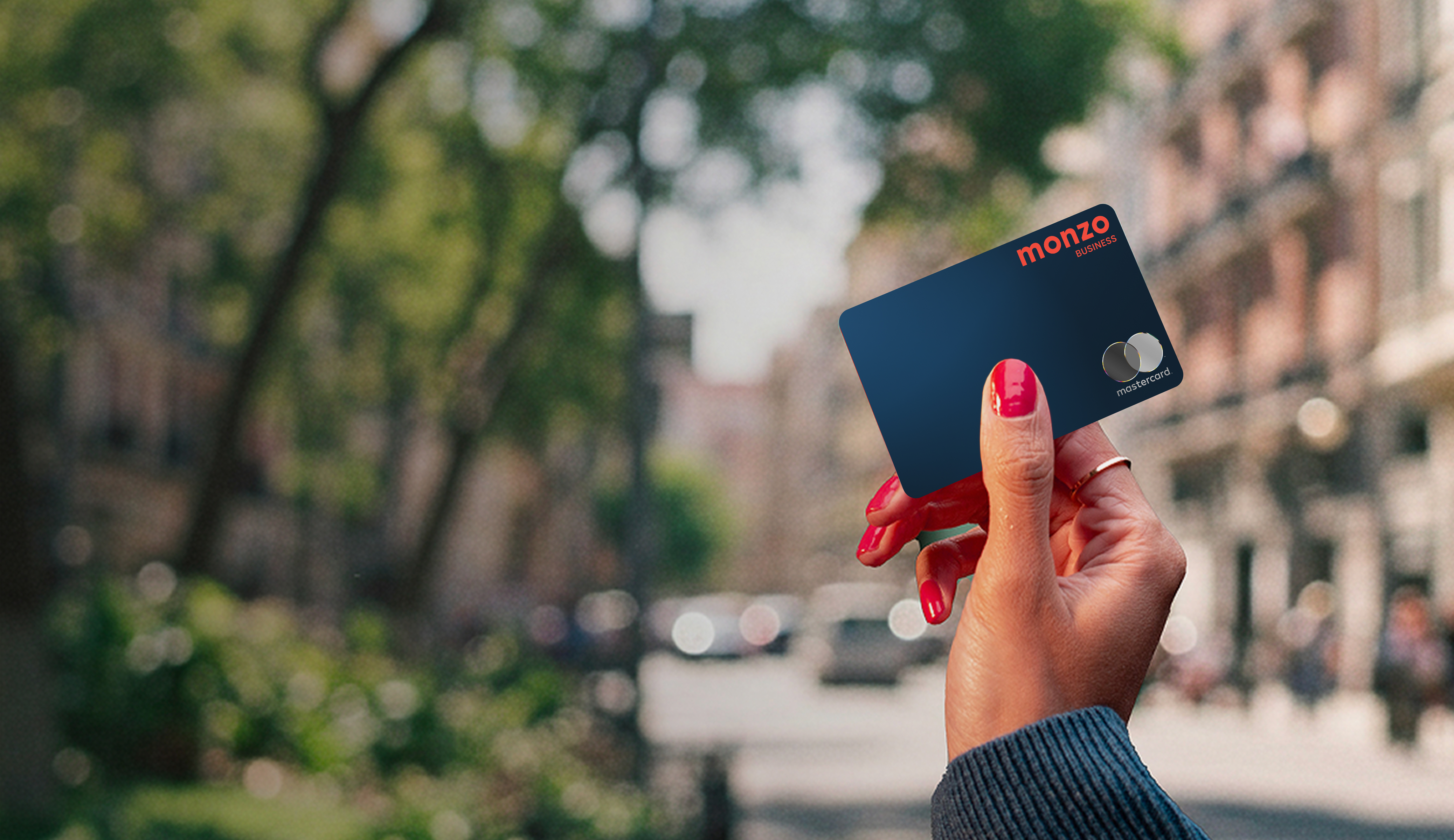 Hand with nail polish holding a Monzo Business debit card