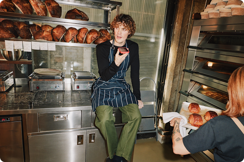 Man speaking into a mobile on a speakerphone in a bakery