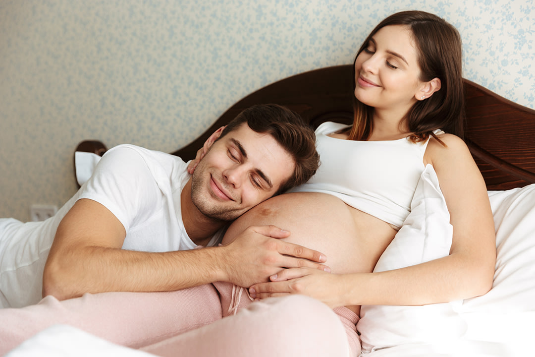 delighted-young-pregnant-wife-lying-bed