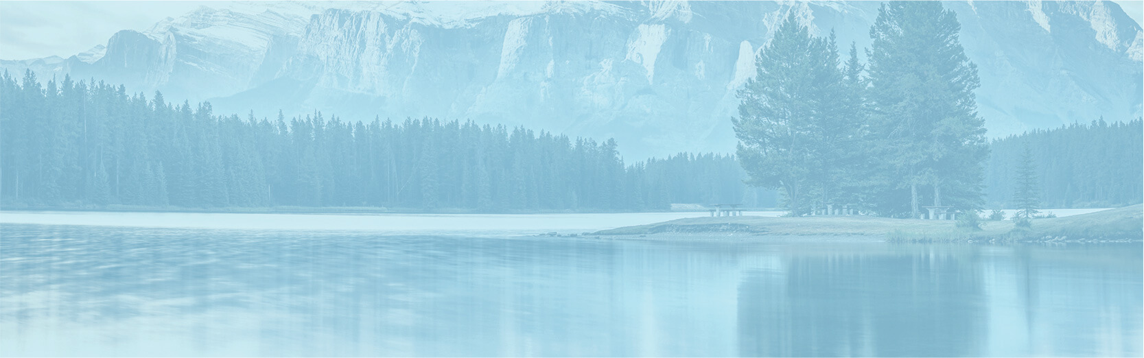 Paysage relaxant de lac, de forêt et de sommets enneigés avec filtre bleu.