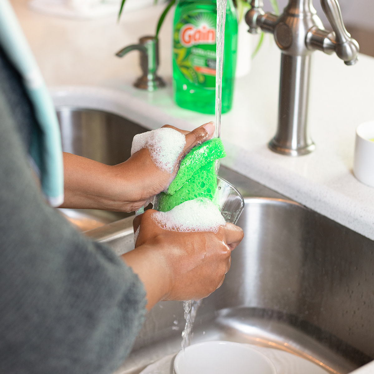 A person washing dishes in a kitchen sink