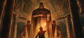 Indiana Jones se encuentra ante tres estatuas de caballeros colosales en una caverna oscura. En la mano, lleva una antorcha que alumbra la antiquísima estancia.
