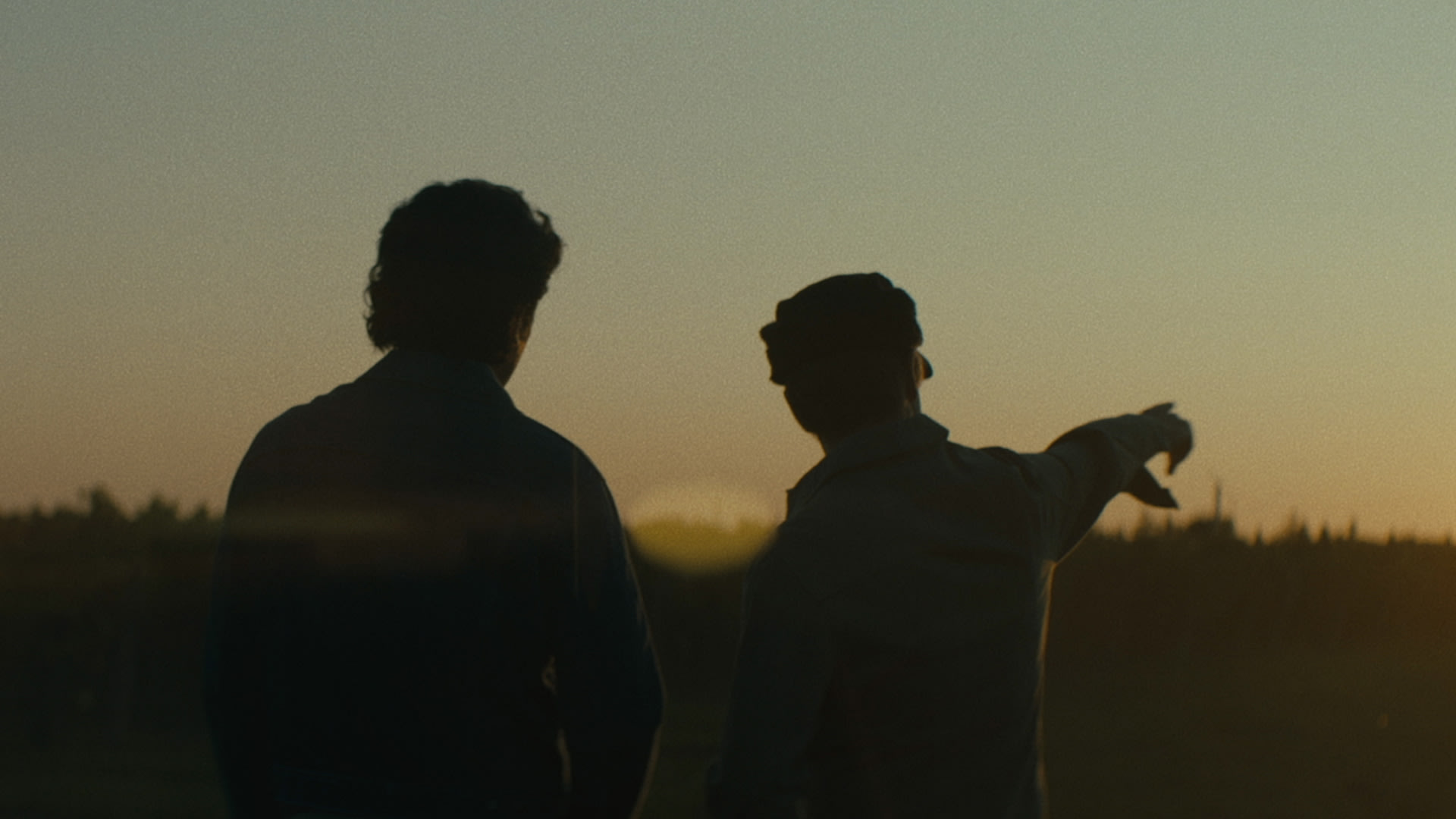 Men pointing to the horizon at sunset