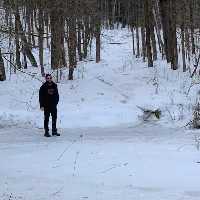 Dan Hemerlein wearing all black on a winter hike in Vermont.