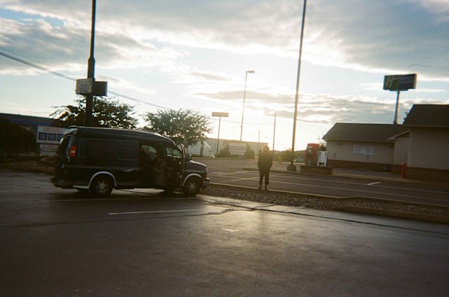 Person standing in a parking lot next to a camper van.