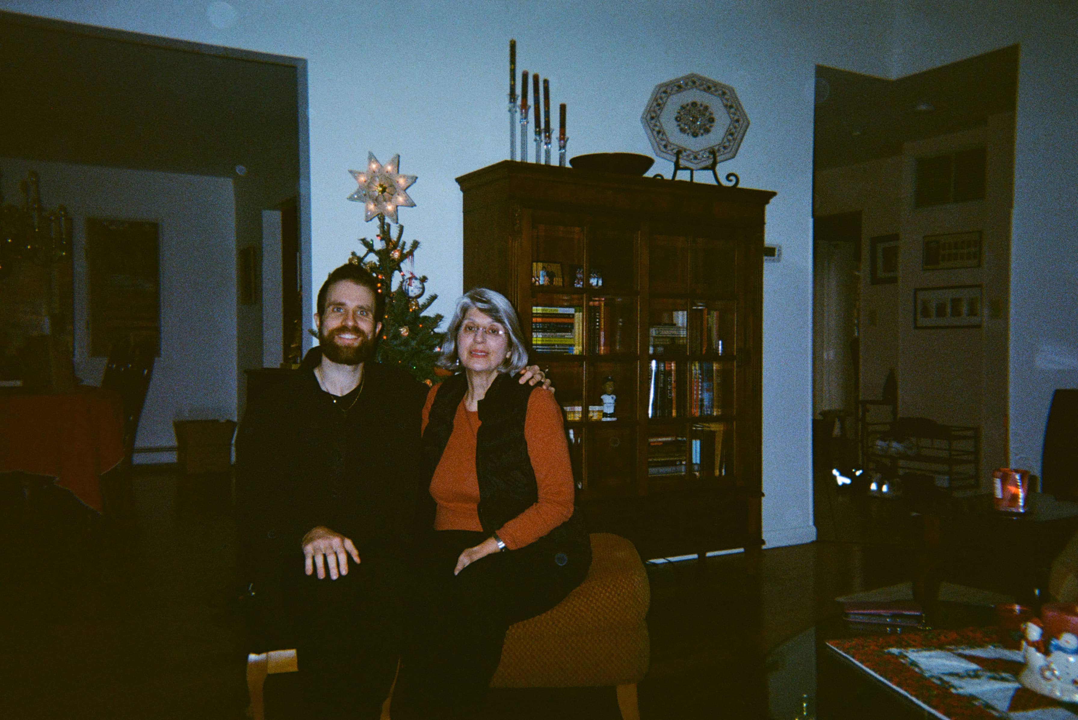 Two people seated in front of a Christmas tree.