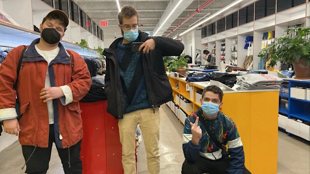 Three people posing for a mirror selfie in a clothing store.