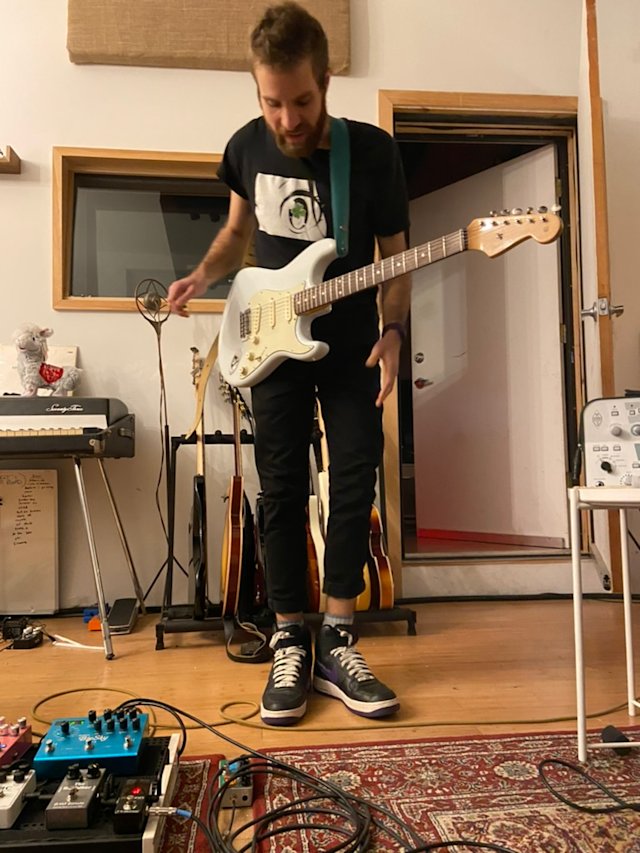 Person playing electric guitar in a recording studio.