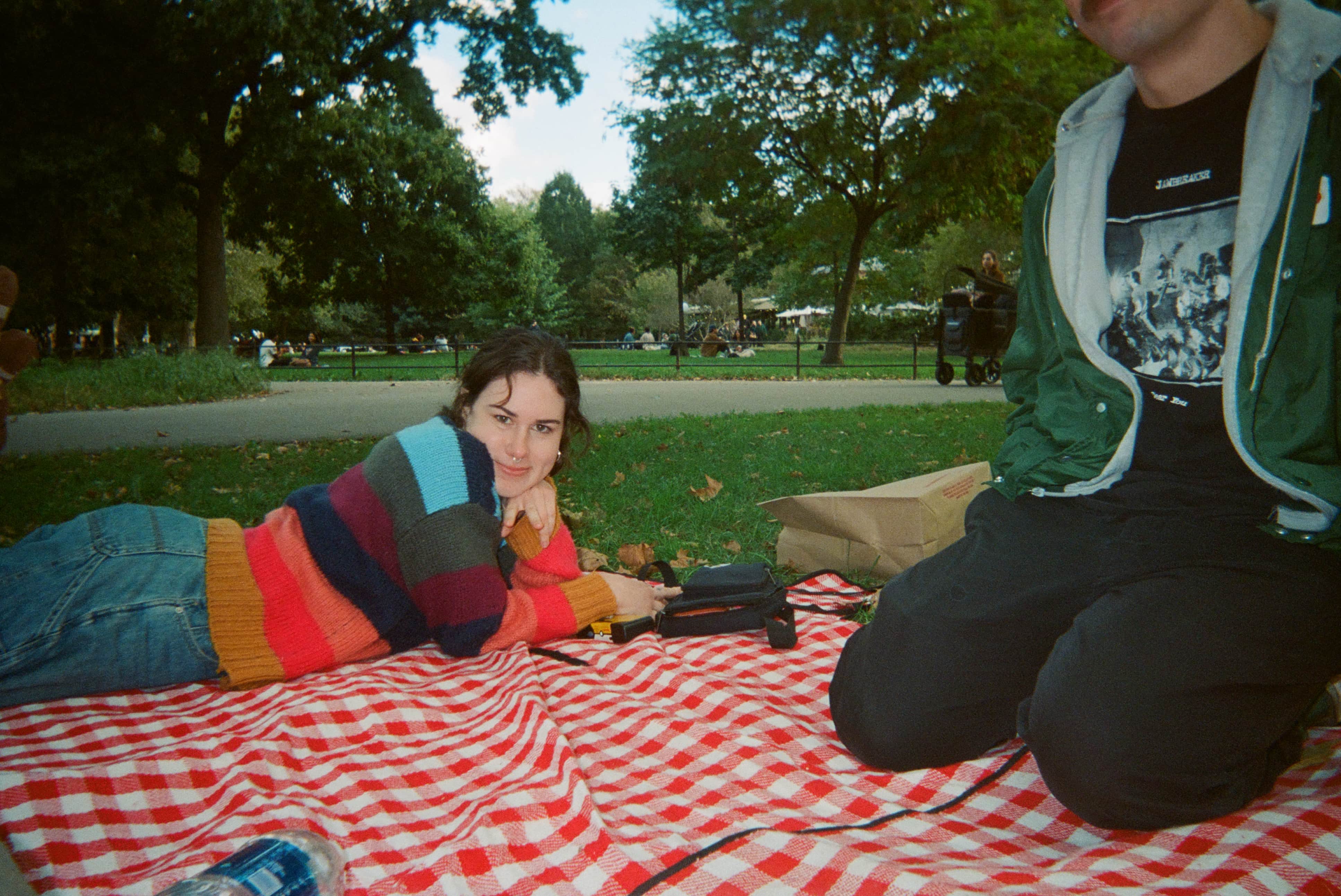 A person lying on a blanket in a park.
