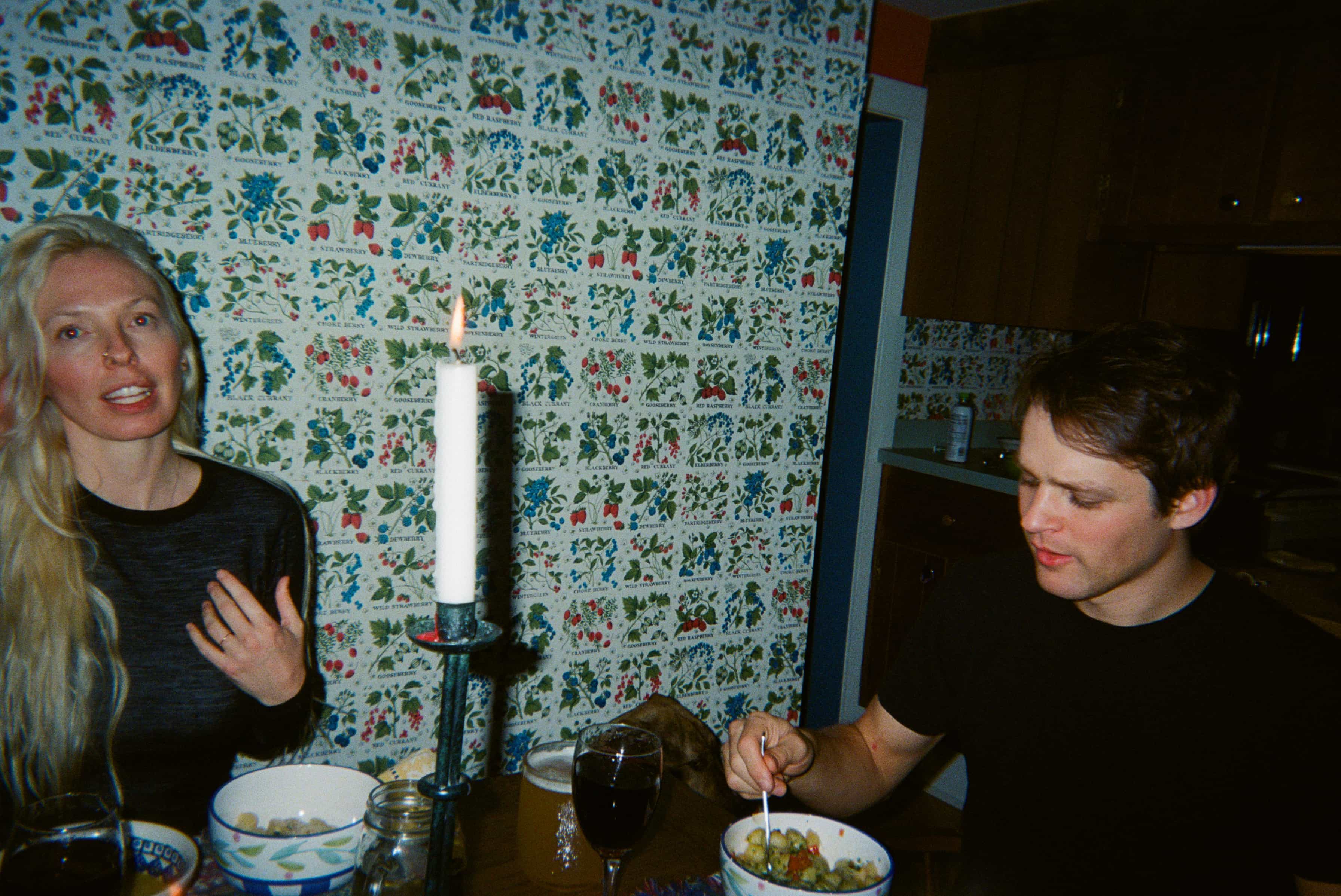 Two people sitting at a table with a candle in front of them.