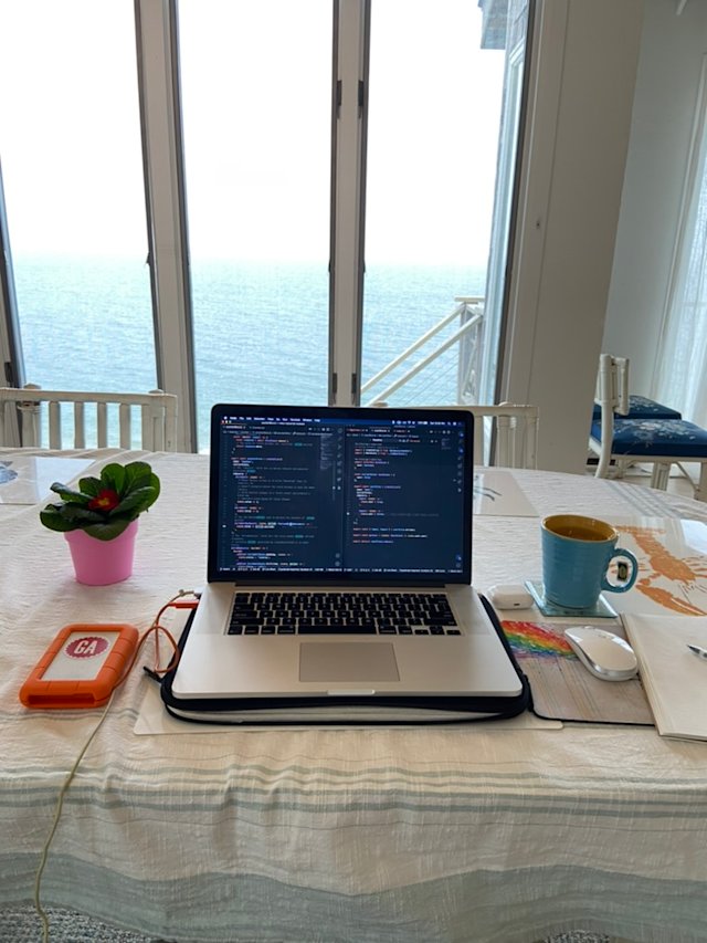 A laptop on a wicker table overlooking Cape Cod Bay.