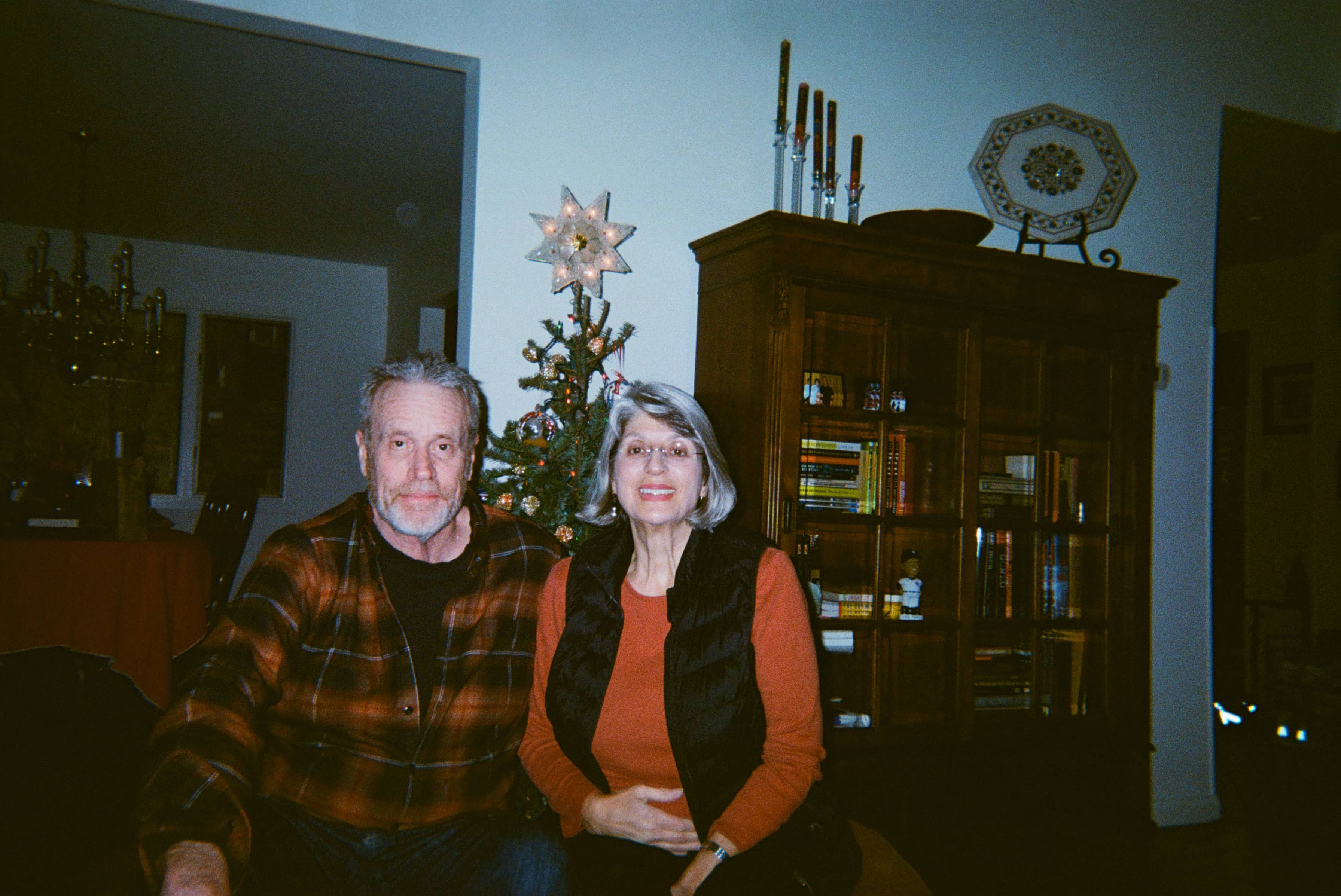 Two people seated in front of a Christmas tree.