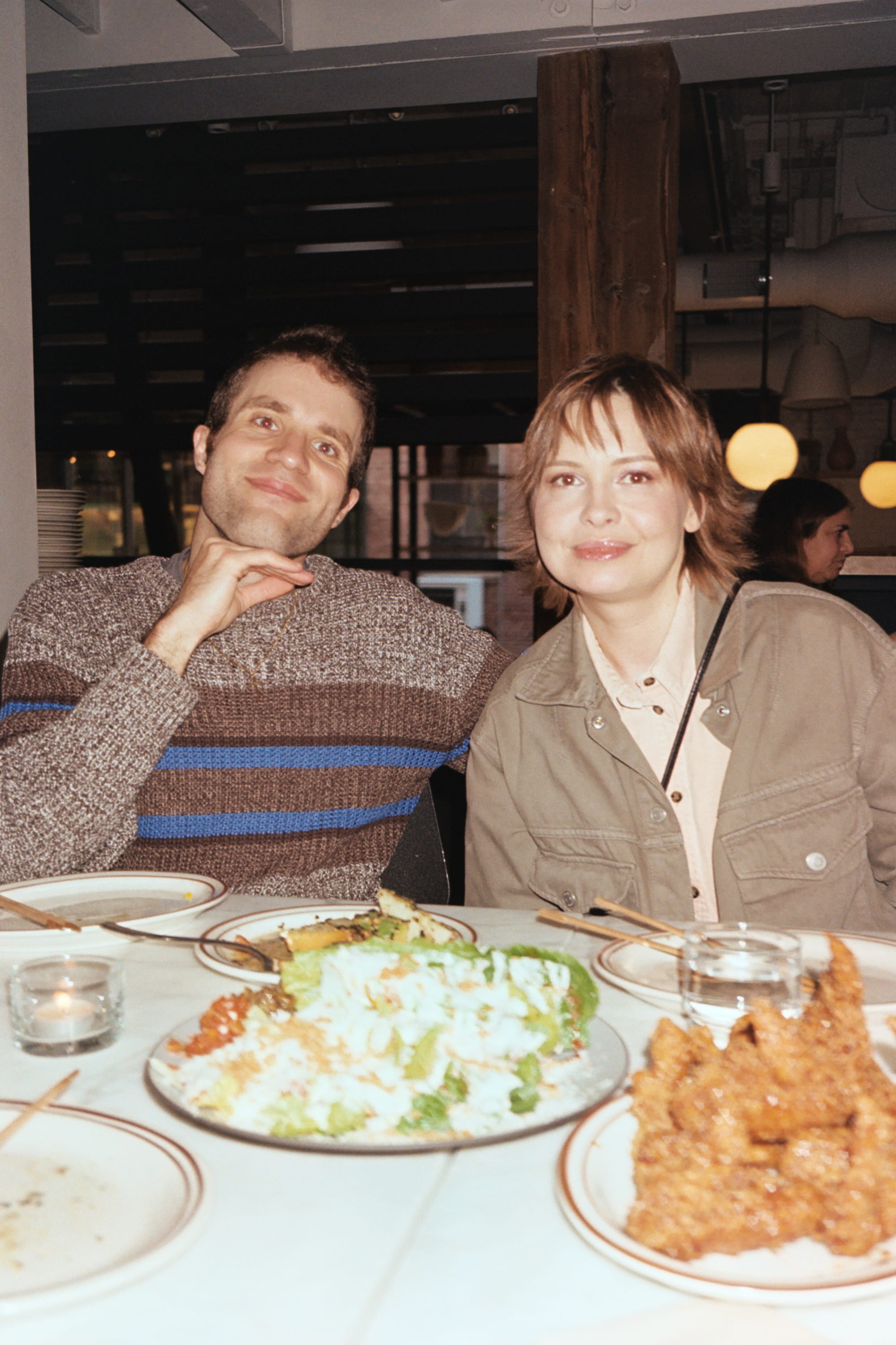Two people sitting at a table with food.